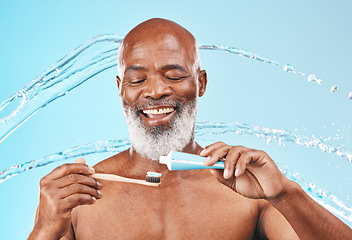 Image showing Face, water splash and black man with toothbrush and toothpaste in studio isolated on blue background. Dental, oral hygiene and senior male model with product for brushing teeth, cleaning and health.