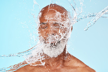 Image showing Elderly black man, water splash and face in studio for wellness, clean or facial health by backdrop. Man, model face and water for skincare, healthy self care or cosmetic beauty by blue background