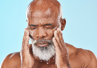 Image showing Black man, face and water drip in studio for cleaning cosmetics, wellness and healthy skincare on blue background. Male model, water splash and wet shower for facial beauty, aesthetic and self care