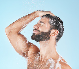 Image showing Face, water splash and shampoo shower of man in studio isolated on a blue background. Water drops, hair care hygiene and male model washing, cleaning or bathing for healthy skin, wellness or skincare