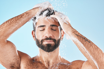 Image showing Hair care, face water splash and shower of man in studio isolated on a blue background. Water drops, shampoo and male model washing, cleaning or bathing for healthy skin, wellness or skincare hygiene