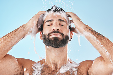 Image showing Shower, man and cleaning for skincare, wellness and hygiene on blue studio background. Arabic male, guy and wash face, hair and hydration for self care, health or body care for cleanliness or routine