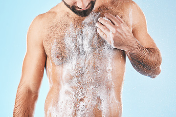 Image showing Shower, water and man with soap on body for cleaning, washing and hygiene on blue background studio. Grooming, bathroom and torso of male with foam sponge for skincare, spa wellness and body care