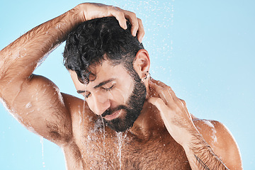 Image showing Hair care, face and water splash of man in shower in studio isolated on a blue background. Water drops, dermatology and male model washing, cleaning or bathing for skincare, wellness and hygiene.