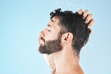 Image showing Water splash, face and man in shower for skincare in studio on a blue background mock up. Dermatology, water drops and profile of male model cleaning, bathing or washing for healthy skin and hygiene.