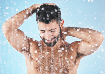 Image showing Face, water splash and skincare shower of man in studio isolated on a blue background. Dermatology, water drops and male model bathing, washing or cleaning for hygiene, wellness and healthy skin.