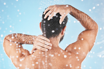 Image showing Face, back and water splash of man in shower in studio on a blue background. Water drops, dermatology and male model washing, cleaning or bathing for fresh hygiene, skincare wellness or healthy skin.