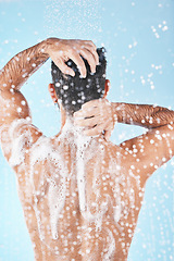 Image showing Shower, water and man cleaning body with soap, foam and hair products on blue background in studio. Bathroom hygiene, grooming and back of male washing body for self care, spa wellness and skincare