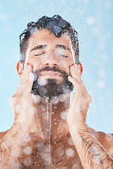 Image showing Face, skincare shower and water splash of man in studio isolated on a blue background. Water drops, dermatology and male model washing, cleaning or bathing for healthy skin, wellness and hygiene.