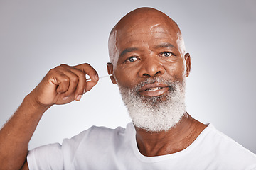 Image showing Senior black man, ears cleaning and cotton bud for wax removal, grooming hygiene and self care cosmetics earwax cleaner in white studio background. Elderly african model, face and body care cleansing