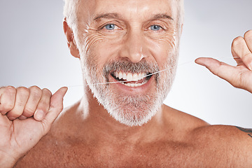 Image showing Dental floss, portrait of man and teeth for wellness, healthy lifestyle and oral hygiene on studio background. Happy male face, flossing tooth and cleaning mouth, beauty cosmetics and facial smile