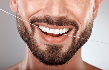 Image showing Dentist, floss and mouth of man with smile on gray background in studio for wellness, healthcare and hygiene. Dental care, grooming and zoom of male model for dentistry, cleaning and flossing teeth