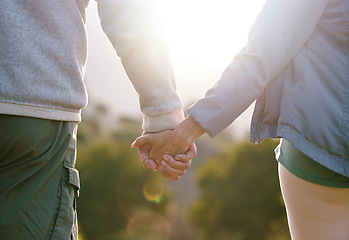 Image showing Couple, holding hands with lens flare and outdoor in nature, love and bond with relationship and commitment with travel and adventure. Man, woman and hand holding, trust and support in the park.