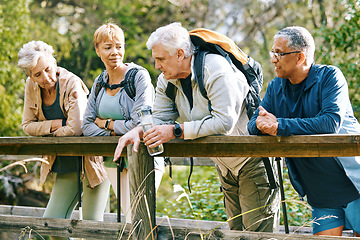 Image showing Elderly, people hiking and happy in park with fitness outdoor, relax on bridge while trekking in nature together. Health, wellness and hiker group, sport and active lifestyle motivation with cardio.