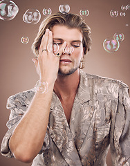 Image showing Beauty, fashion and man with bubbles in studio on brown background for cosmetics, style and modern outfit. Creative art, luxury design and male fashion model with soap bubbles, jewellery and makeup