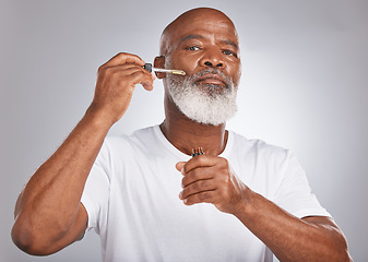 Image showing Senior man, face serum and skincare with dermatology and cosmetics for clean, glow and fresh skin. Portrait of a black male with a pipette for collagen oil on a grey studio background for beauty