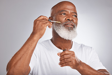 Image showing Skincare, wellness and man with a face serum in a studio for a healthy, cosmetic and natural routine. Beauty, cosmetics and African male with a facial oil treatment isolated by a gray background.