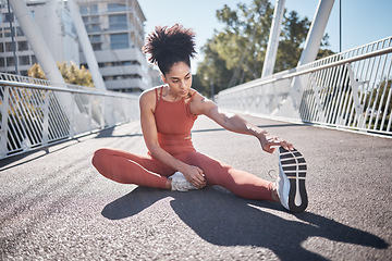 Image showing Stretching legs, fitness and black woman on city bridge for exercise, running or training in sports shoes fashion. Warm up, focus and urban athlete on ground workout for body, muscle and health goals