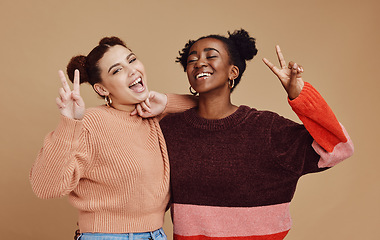 Image showing Fashion, peace sign and women friends in studio with hand gesture, smile and happiness on brown background. Freedom, beauty and black woman with happy girl for relaxing, cosmetics and emoji together