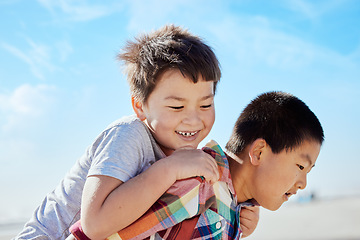 Image showing Asian kids, siblings and piggyback on the beach for fun summer vacation together in the outdoors. Happy Japanese children with smile playing by the ocean coast on a back ride on a warm sunny day