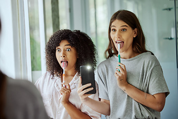 Image showing Friends, wellness and brushing teeth phone selfie with crazy face for morning hygiene routine in home. Comic, goofy and interracial friendship of women cleaning teeth with smartphone photograph.