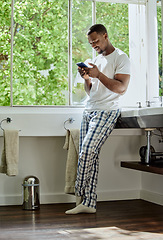 Image showing Home, phone and black man in bathroom on social media, texting or internet browsing. Relax, cellphone or happy male holding mobile smartphone for web scrolling, networking or messaging alone in house