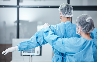 Image showing Doctor, uniform and surgeon prepare for surgery, operation or medical healthcare. Nurse helping worker with safety clothing in emergency operating room, hospital and wellness support, theater or risk