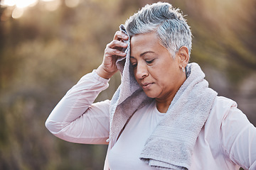 Image showing Fitness, towel and tired senior woman outdoor sweating in nature after running for cardio workout, health and wellness. Elderly female wiping sweat in a forest after a run for healthy lifestyle