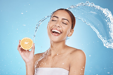 Image showing Water splash, orange fruit and skincare happiness in blue studio background for organic facial care cleaning, dermatology detox and spa nutrition. Model face, smile and vitamin c and citrus cosmetics