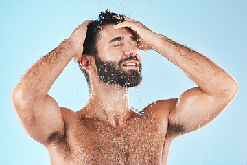 Image showing Water, shower and hair with a man cleaning using shampoo in studio on a blue background for beauty or hygiene. Washing, clean and keratin with a handsome male wet in a bathroom for natural haircare