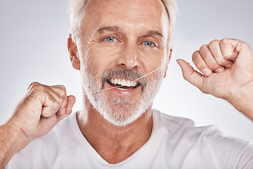 Image showing Face, dental floss and senior man in studio isolated on a gray background. Portrait, cleaning and elderly male model with product flossing teeth for oral wellness, tooth care and healthy gum hygiene