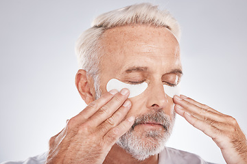 Image showing Eyes patch, senior man and skincare face in studio for self care dermatology, facial and cosmetics advertising in morning. Model with hands application of collagen mask or anti aging beauty product