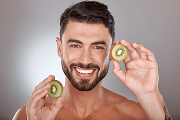 Image showing Man, face and beauty with kiwi, facial care with wellness and organic treatment against studio background. Natural skincare, exotic fruit and wellness with cosmetic care and smile in portrait
