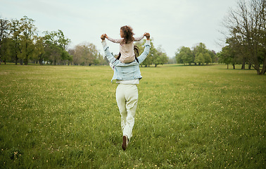 Image showing Mother, child and piggyback in the nature countryside for bonding relationship, freedom or weekend travel. Mom holding daughter on back playing together for fun in the park on the open green field