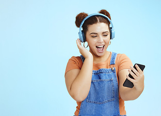 Image showing Mockup, smartphone and woman with headphones, excited and smile on blue studio background. Happy, female or girl with cellphone, headset or steaming music, social media or podcast to relax or listen