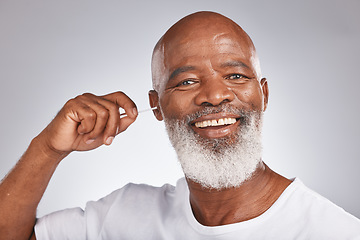 Image showing Portrait, cotton and a black man cleaning his ear in studio on a gray background for hygiene or grooming. Earbud, face and smile with a happy senior male in the bathroom to clean out earwax