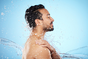 Image showing Man, water splash and clean for skincare, wellness and health with beauty, grooming and on blue studio background. Cleaning, male and shower for washing, organic care and hygiene for natural skin.