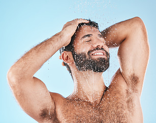 Image showing Shower, grooming and a man cleaning his hair with shampoo in studio on a blue background for beauty. Hygiene, washing and bathroom with a handsome male wet with liquid while bathing for haircare