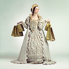 Image showing Queen, fashion bags and woman shopping in studio isolated on a gray background mockup. Royalty, sales deals and rich and wealthy female ruler holding luxury golden gifts after purchase at royal mall.