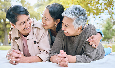 Image showing Love, family and lesbian couple with adult daughter, happy and laughing, relax and talking in a park. Lgbt, happy family and woman enjoying a picnic with her mothers, cheerful and excited while lying