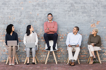 Image showing Creative business people, waiting room and man standing out against a brick wall for interview, meeting or opportunity. Group of employee interns with technology looking at candidate for startup