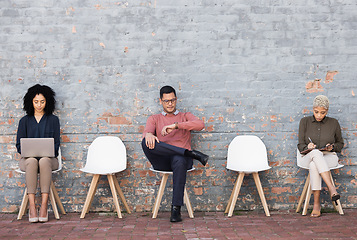 Image showing Business people, waiting room and sitting on chairs against brick wall for interview, meeting or opportunity. Group of creative interns in social distancing, working and checking time for startup