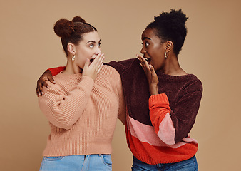 Image showing Gossip, friends and surprise face of young women with a secret and brown studio background. Wow, student surprised and girl chat together with whisper and excited discussion with shock from story