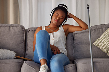 Image showing Black woman, sleeping and listening to music on sofa in the living room after housekeeping, cleaning or dusting at home. African American female domestic relaxing or resting with headphones on couch