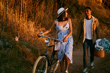 Image showing Romantic, happy and couple on a picnic in a park for a date, holiday and love in Indonesia. Travel, smile and man and woman walking in nature for romance, peace and relax with food during sunset