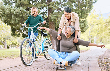 Image showing Comic, happy and retirement friends in park for silly outdoor fun with skateboard and bicycle. Funny, goofy and senior women in nature with excited smile for bonding wellness together.