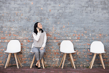 Image showing Phone call, queue and woman from Japan on chairs, recruitment and employment with smile at interview. Happy person sitting on chair, wall and smartphone smiling and talking of opportunity for people.