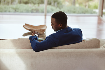 Image showing Time, businessman and waiting on a sofa for appointment, meeting or property showing. Watch, realtor and black man sitting in a living room, timing, schedule and new house property investment