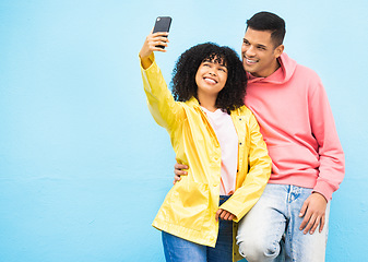 Image showing Friends, phone and smile for selfie on a blue background for fashion, style or friendship together. Young man and woman smiling and looking at smartphone for photo leaning on a wall mockup