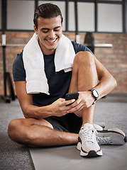 Image showing Fitness, man and phone with smile for social media, conversations or chatting while sitting on a mat at gym. Happy sporty male, person or guy smiling in happiness on smartphone after intense workout